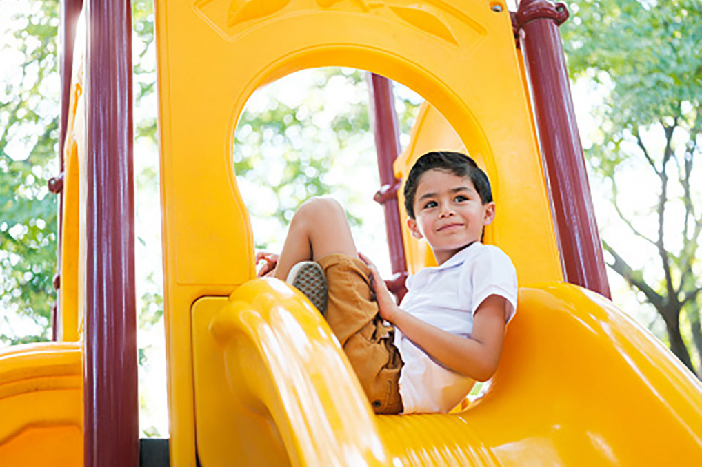 young boy on playground slide